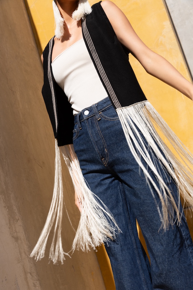 Close-up of handwoven detailing and fringe on the Agave Fringe Vest, styled over a fitted top and white trousers.