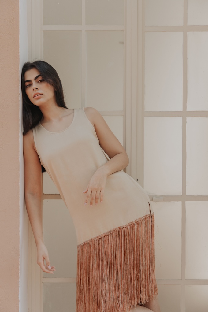 Model wearing the Ceiba Fringe Dress with hand‑stitched fringe hem, styled with artisan Maya earrings and sandals.