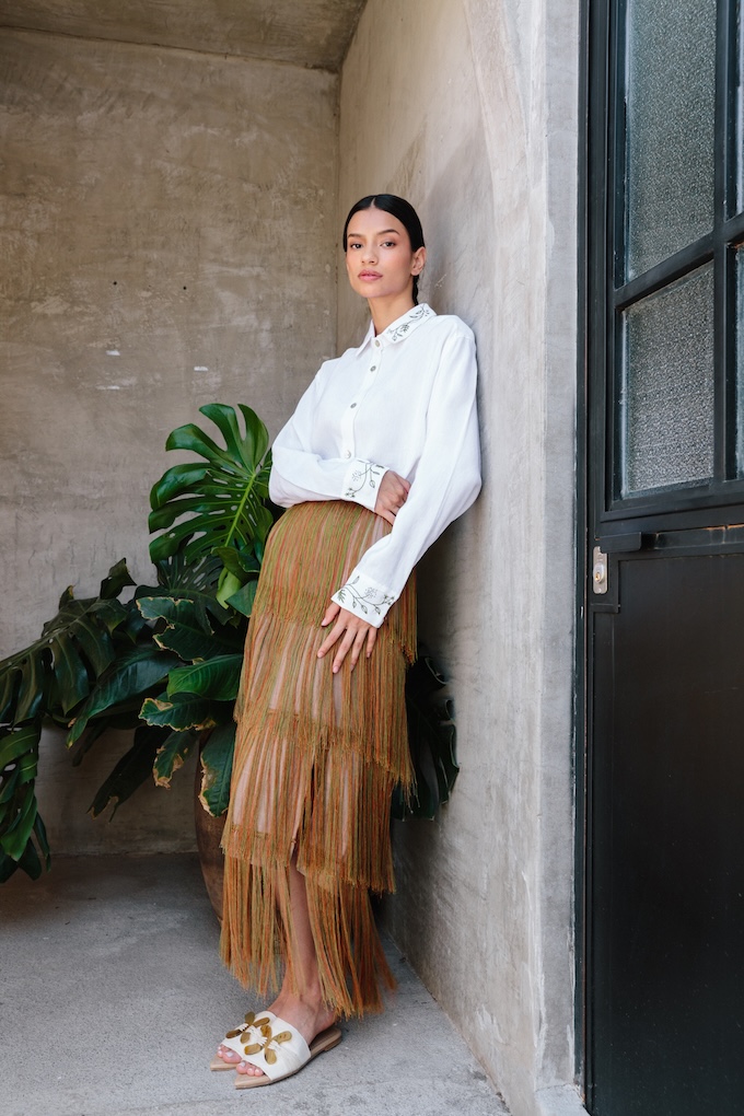 Model wearing the Tule Fringe Maxi Skirt with tiered fringe design, handcrafted by artisans in Chiapas, styled with embroidered blouse.