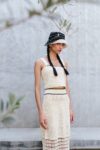 Woman wearing the ivory crochet crop top from the Tequila set, with matching midi skirt and black-and-white bucket hat